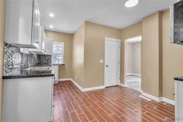 kitchen with decorative backsplash, dark hardwood / wood-style flooring, white cabinetry, and sink