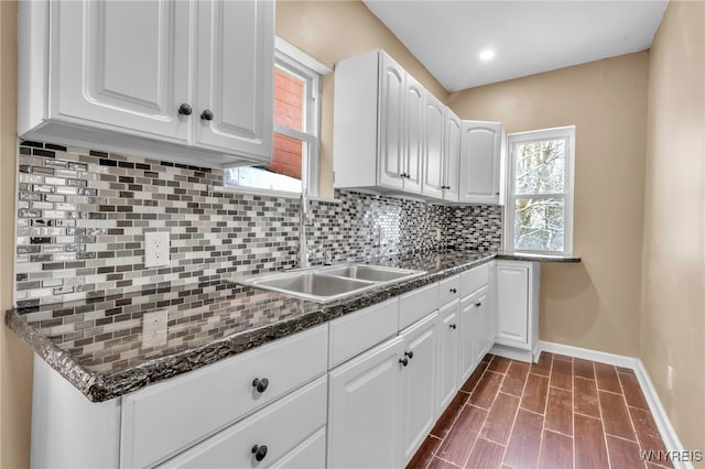 kitchen featuring dark stone countertops, white cabinetry, sink, and decorative backsplash