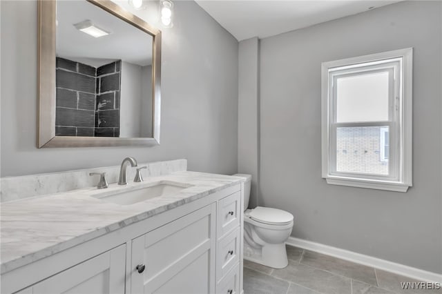 bathroom with tile patterned floors, vanity, toilet, and a healthy amount of sunlight