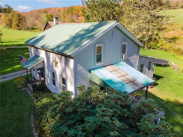 rear view of house with cooling unit, a trampoline, and a yard