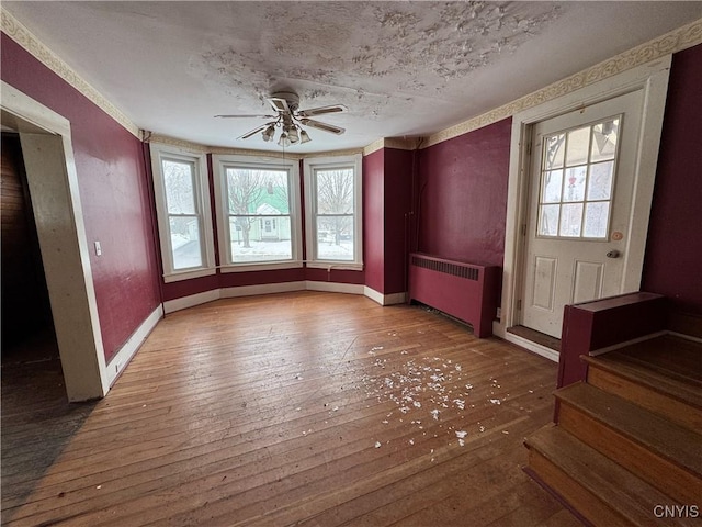 interior space with a textured ceiling, hardwood / wood-style flooring, radiator, and ceiling fan