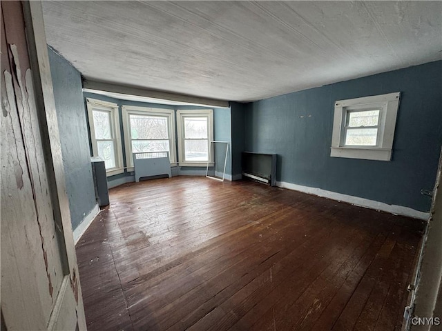 spare room with dark wood-type flooring and a healthy amount of sunlight