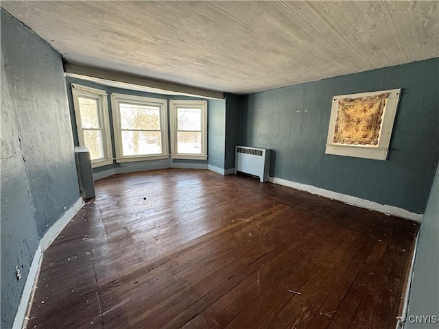 unfurnished living room featuring dark hardwood / wood-style floors and radiator heating unit