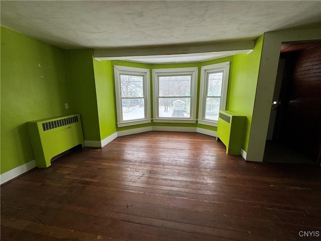 empty room featuring dark hardwood / wood-style floors, radiator heating unit, and a textured ceiling