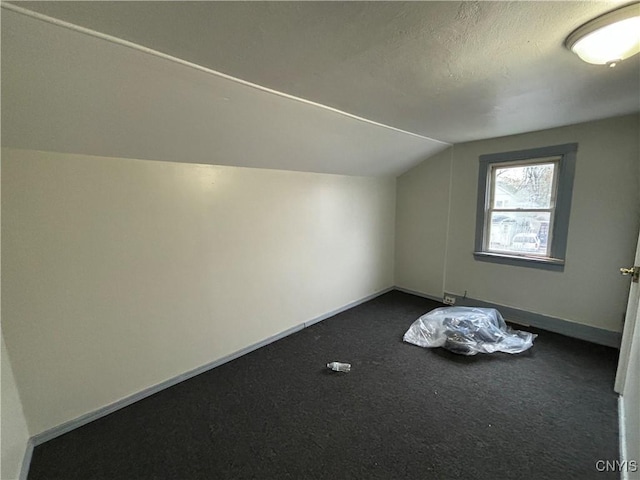 bonus room featuring dark carpet and lofted ceiling