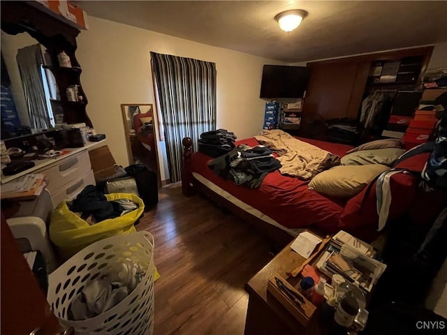 bedroom with dark hardwood / wood-style flooring and a closet