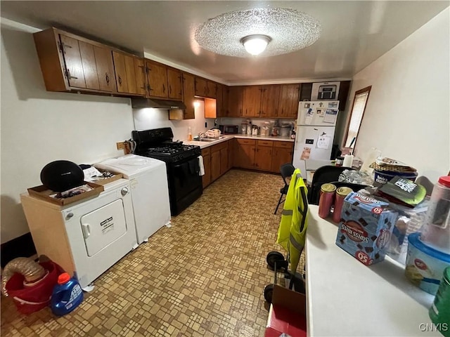 kitchen with washer and clothes dryer, sink, a textured ceiling, white fridge, and gas stove