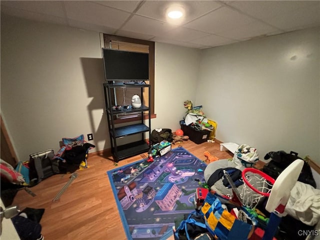 playroom with wood-type flooring and a paneled ceiling