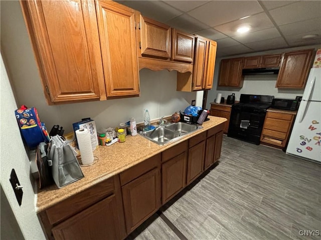 kitchen featuring black appliances, a drop ceiling, and sink