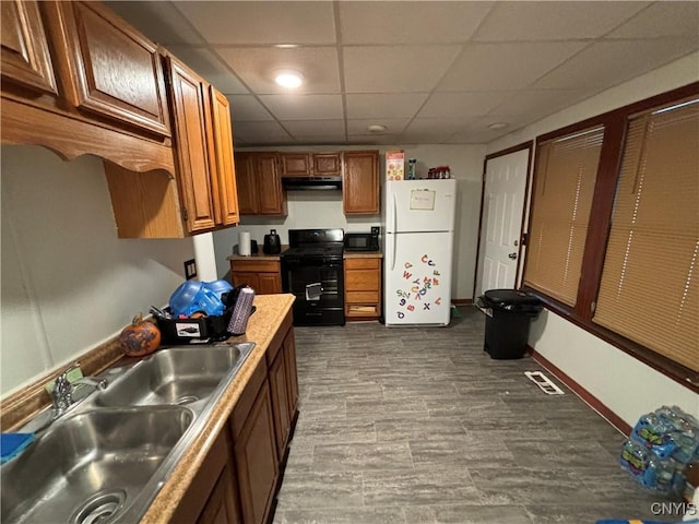 kitchen with sink, wood-type flooring, black appliances, and a drop ceiling