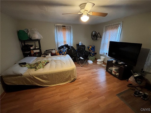 bedroom featuring hardwood / wood-style floors, ceiling fan, and multiple windows