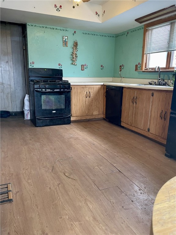 kitchen with black appliances, light wood-type flooring, and sink