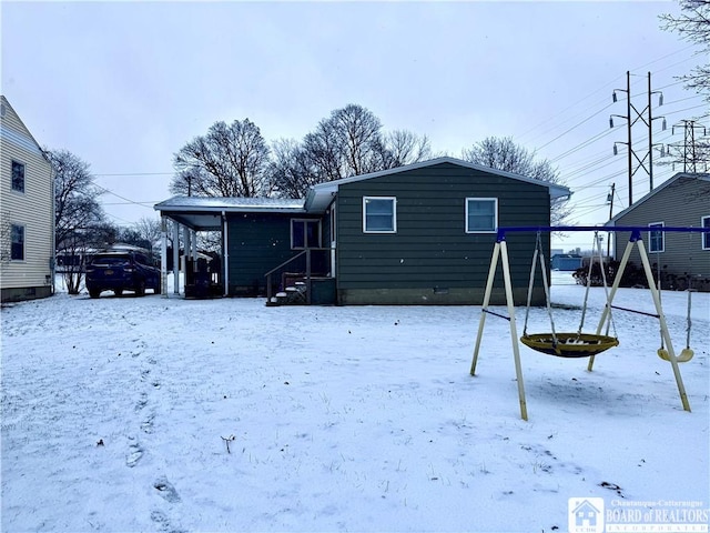 snow covered house featuring a playground