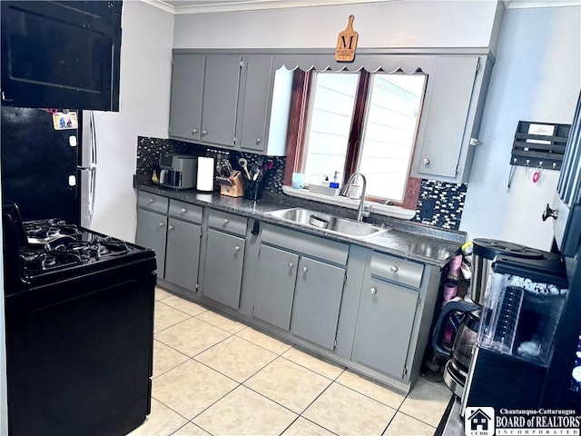 kitchen featuring black gas range, gray cabinets, and sink