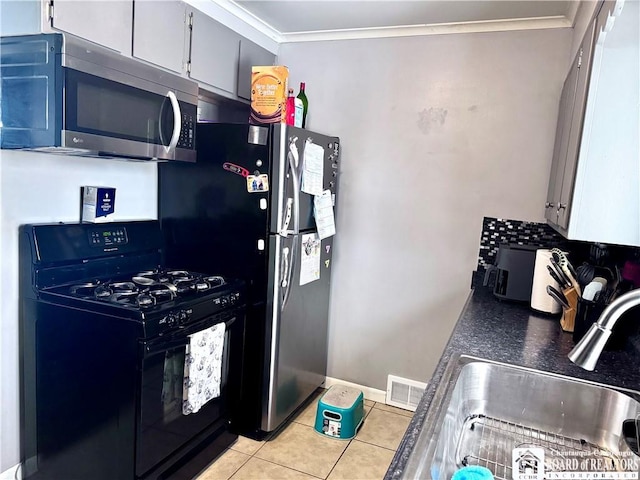 kitchen with crown molding, black gas stove, light tile patterned floors, and sink