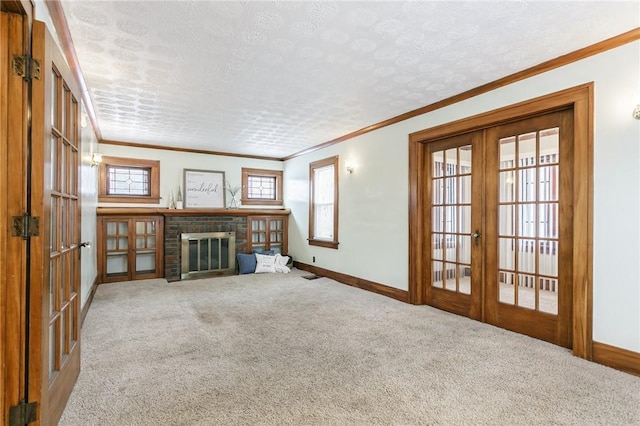 unfurnished living room with carpet, ornamental molding, a fireplace, and french doors