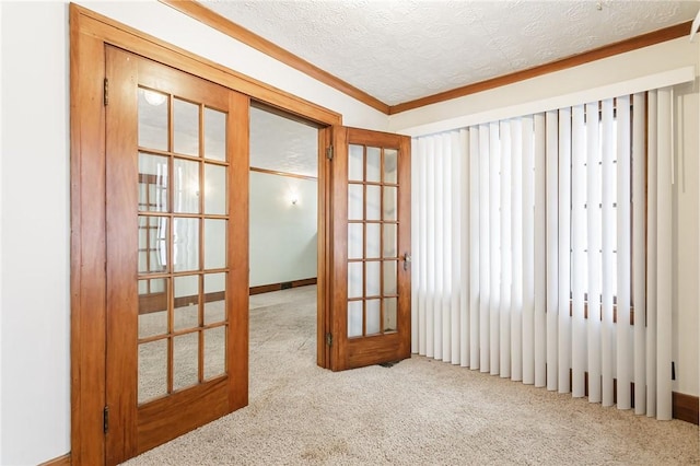 spare room featuring crown molding, light colored carpet, a textured ceiling, and french doors