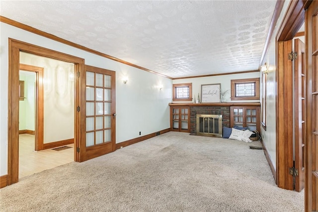 unfurnished living room with a textured ceiling, light colored carpet, ornamental molding, and a fireplace