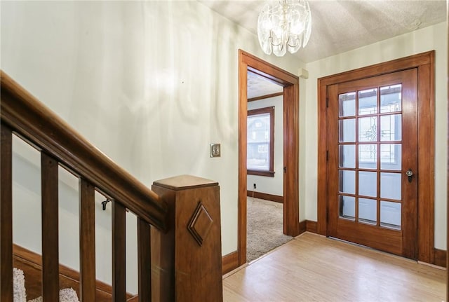 doorway featuring light hardwood / wood-style flooring, a textured ceiling, and an inviting chandelier