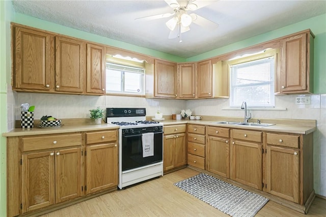 kitchen featuring ceiling fan, sink, light hardwood / wood-style flooring, white range, and a textured ceiling