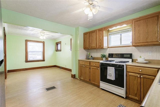 kitchen with white range oven, tasteful backsplash, plenty of natural light, and light wood-type flooring