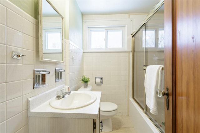 full bathroom with toilet, tile patterned floors, tile walls, and enclosed tub / shower combo