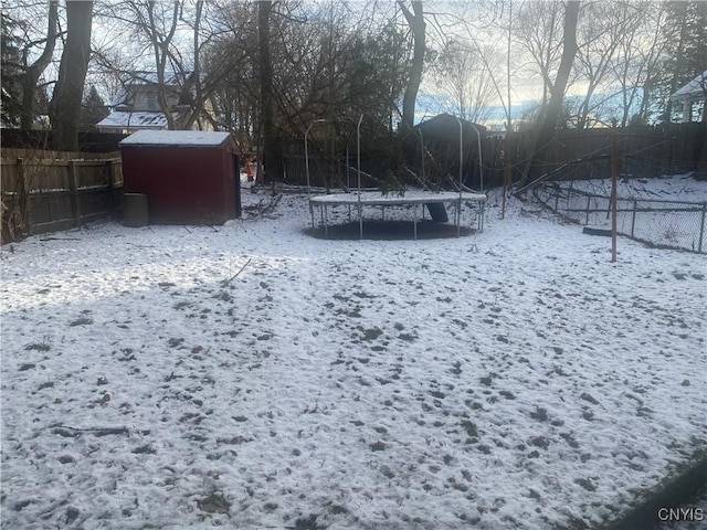 yard layered in snow with a trampoline and a storage unit