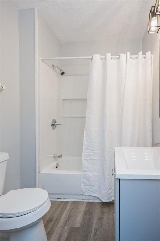 full bathroom with vanity, a textured ceiling, shower / bathtub combination with curtain, hardwood / wood-style floors, and toilet