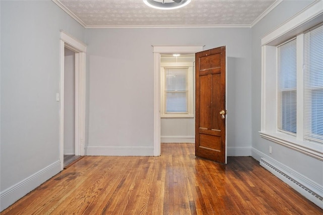 unfurnished room with ornamental molding, a textured ceiling, and a baseboard heating unit