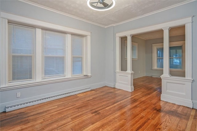 unfurnished room featuring ornate columns, a baseboard heating unit, wood-type flooring, a textured ceiling, and ornamental molding