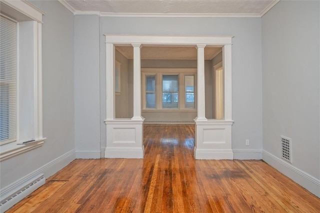 empty room featuring crown molding, a baseboard radiator, and hardwood / wood-style flooring