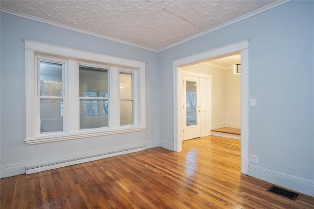 spare room featuring hardwood / wood-style flooring, ornamental molding, a textured ceiling, and a baseboard heating unit