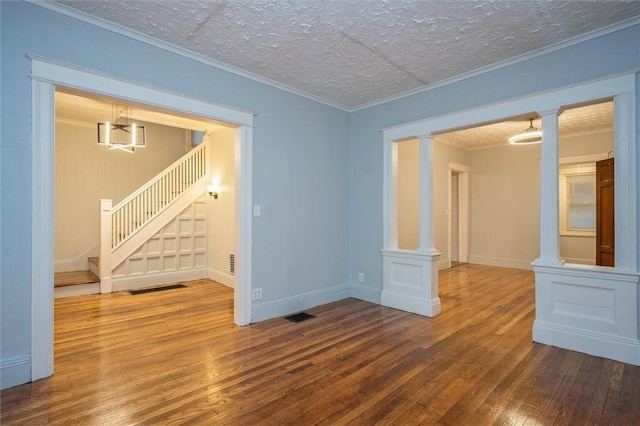 empty room featuring hardwood / wood-style floors, ornamental molding, and a textured ceiling