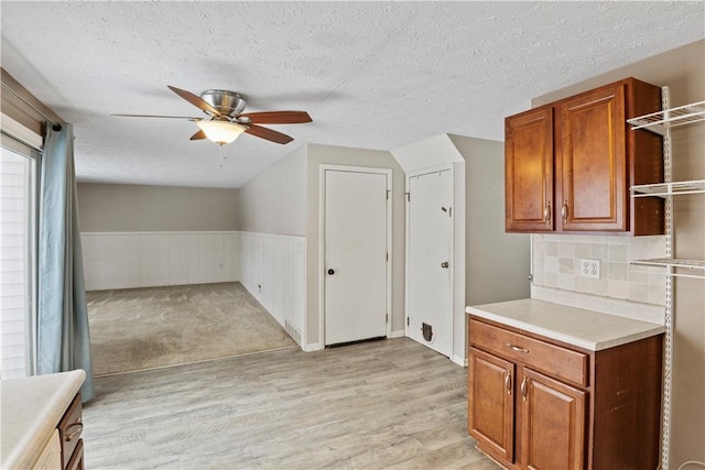 kitchen with backsplash, ceiling fan, light wood-type flooring, and a textured ceiling