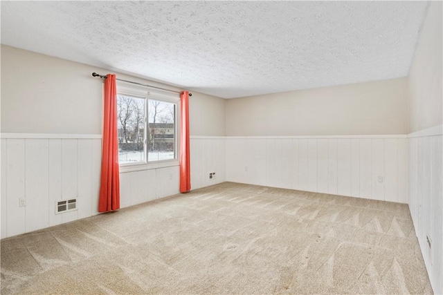 unfurnished room with carpet, a textured ceiling, and wood walls