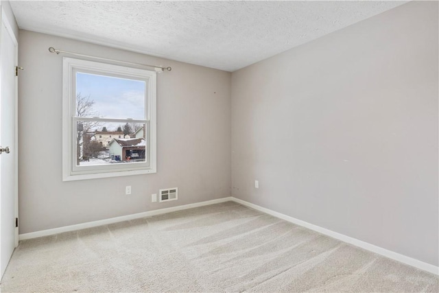 carpeted empty room featuring a textured ceiling