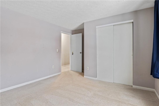 unfurnished bedroom featuring a textured ceiling, light colored carpet, and a closet