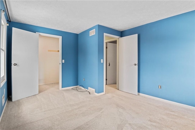 unfurnished bedroom featuring a textured ceiling, light colored carpet, and a closet