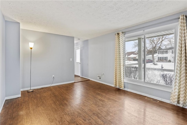 empty room with hardwood / wood-style floors and a textured ceiling