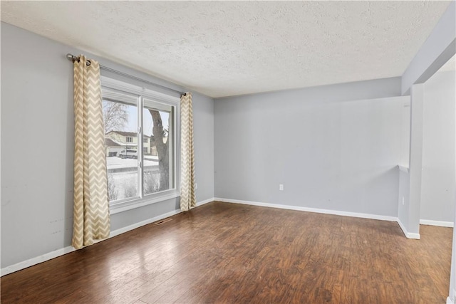 unfurnished room featuring dark hardwood / wood-style flooring and a textured ceiling