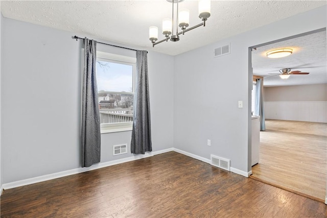 unfurnished room with a textured ceiling, hardwood / wood-style floors, and ceiling fan with notable chandelier