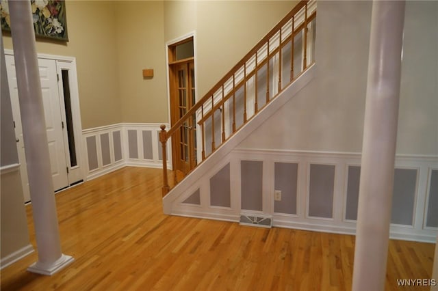 staircase with hardwood / wood-style flooring and ornate columns