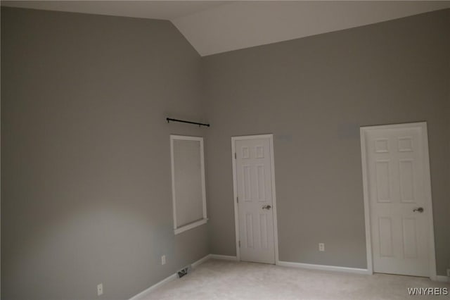 carpeted empty room featuring lofted ceiling