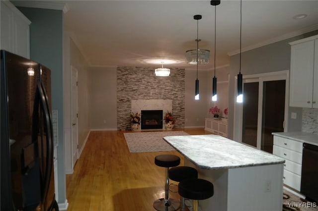 kitchen with white cabinetry, a center island, hanging light fixtures, light hardwood / wood-style flooring, and black appliances