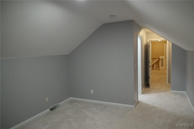 additional living space with light colored carpet and vaulted ceiling