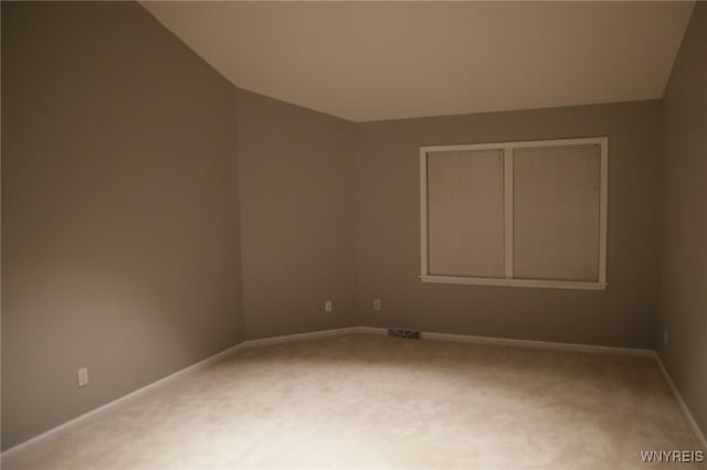 spare room featuring carpet flooring and lofted ceiling