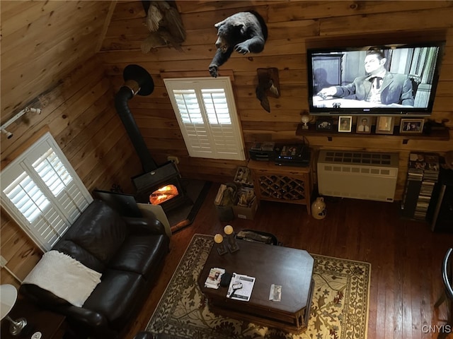 living room with dark hardwood / wood-style floors, a wood stove, and wooden walls