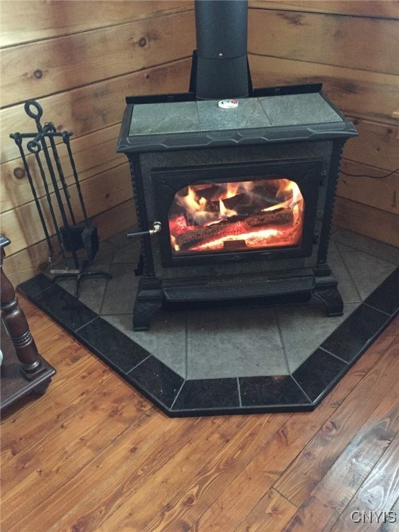 room details featuring a wood stove, wooden walls, and hardwood / wood-style flooring