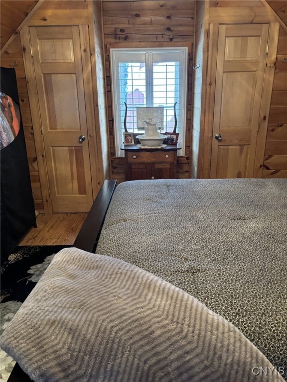 bedroom with vaulted ceiling and wood walls