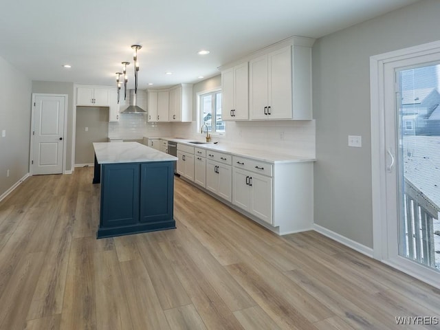 kitchen featuring white cabinetry, backsplash, wall chimney range hood, and a center island